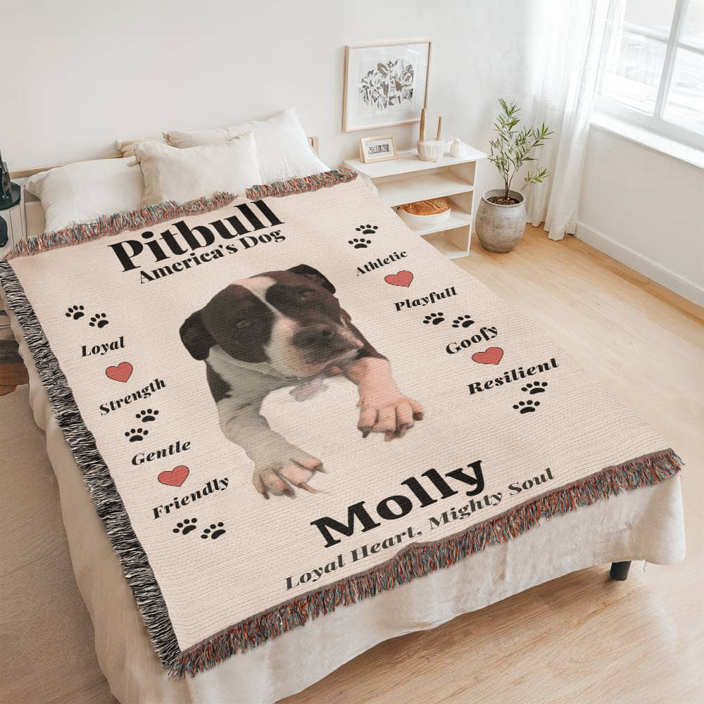 Personalized dog blanket with a pitbull image and text on a bed in a room.