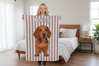 Person holding a striped towel with a dachshund design and 'Daisy' text in a living room.