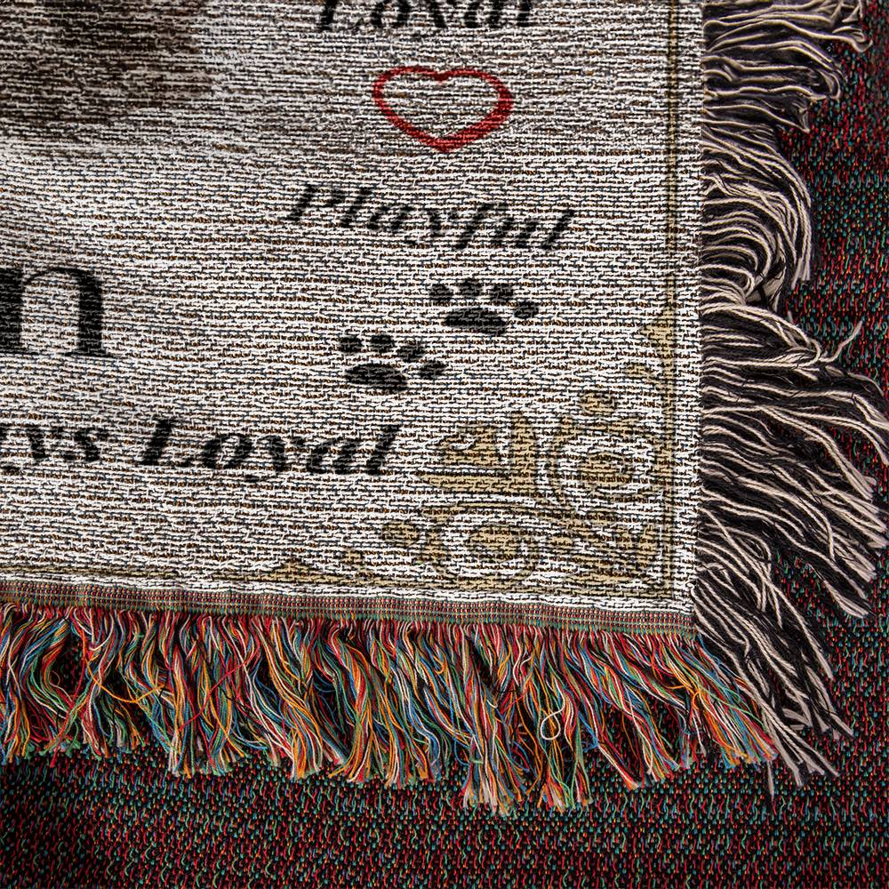 Textured fabric with dog-themed words and graphics, featuring fringes on a dark background.