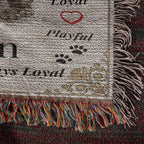 Textured fabric with dog-themed words and graphics, featuring fringes on a dark background.