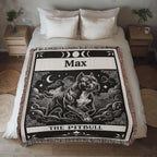 Blanket with a tartot card with a pitbull dog illustration and 'Max' printed on it, draped over a bed.