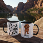 Two mugs with 'Best Dog Dad Ever' and a dachshund illustration on a wooden surface with a scenic background.