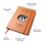 Notebook with a dog's face on the cover, labeled with features like vegan leather cover and brown elastic closure band.
