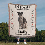 Woven Blanket with a Pitbull illustration and text about the breed, held by a person outdoors.