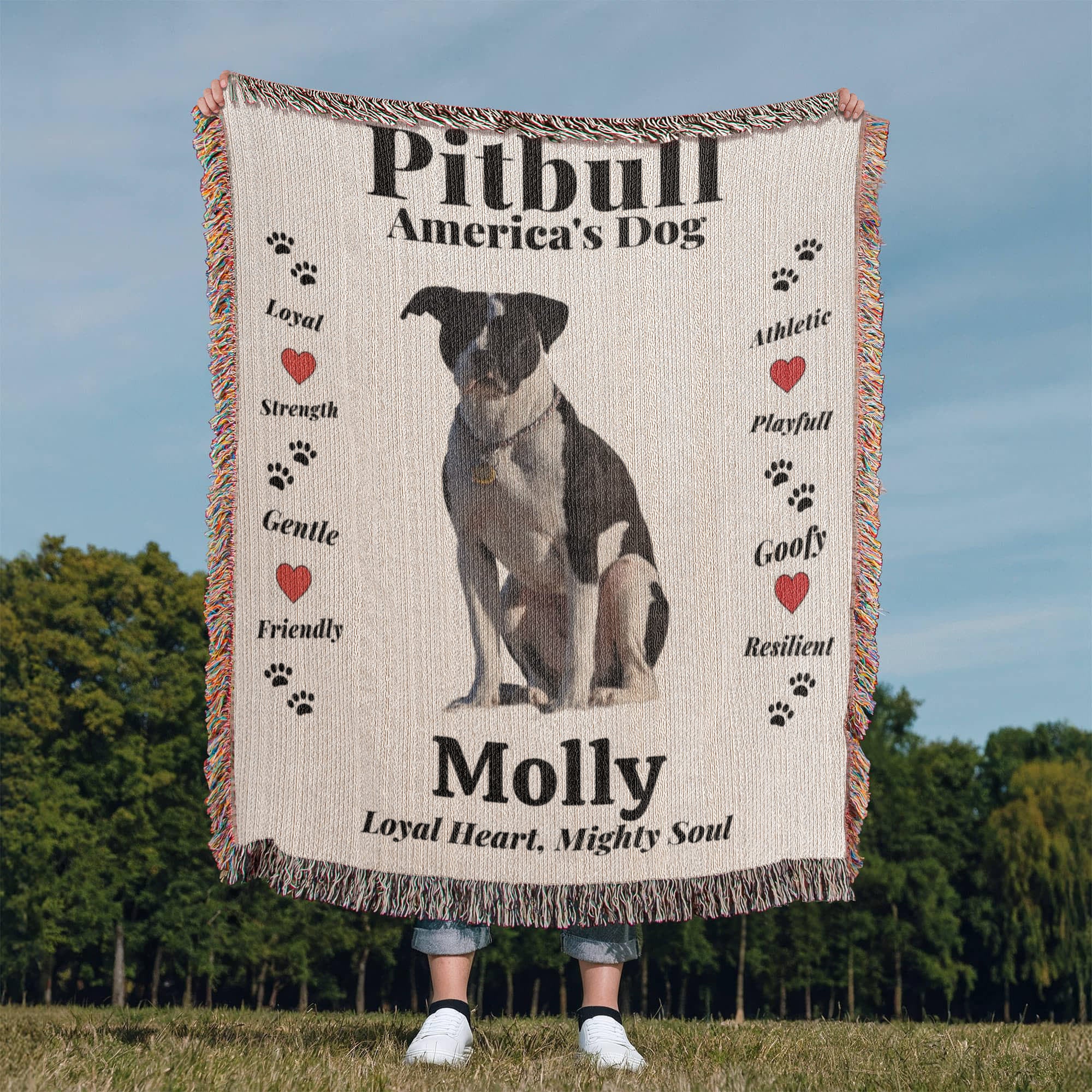 Woven Blanket with a Pitbull illustration and text about the breed, held by a person outdoors.
