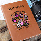 Brown notebook with floral paw design and text, camera and strap in the background
