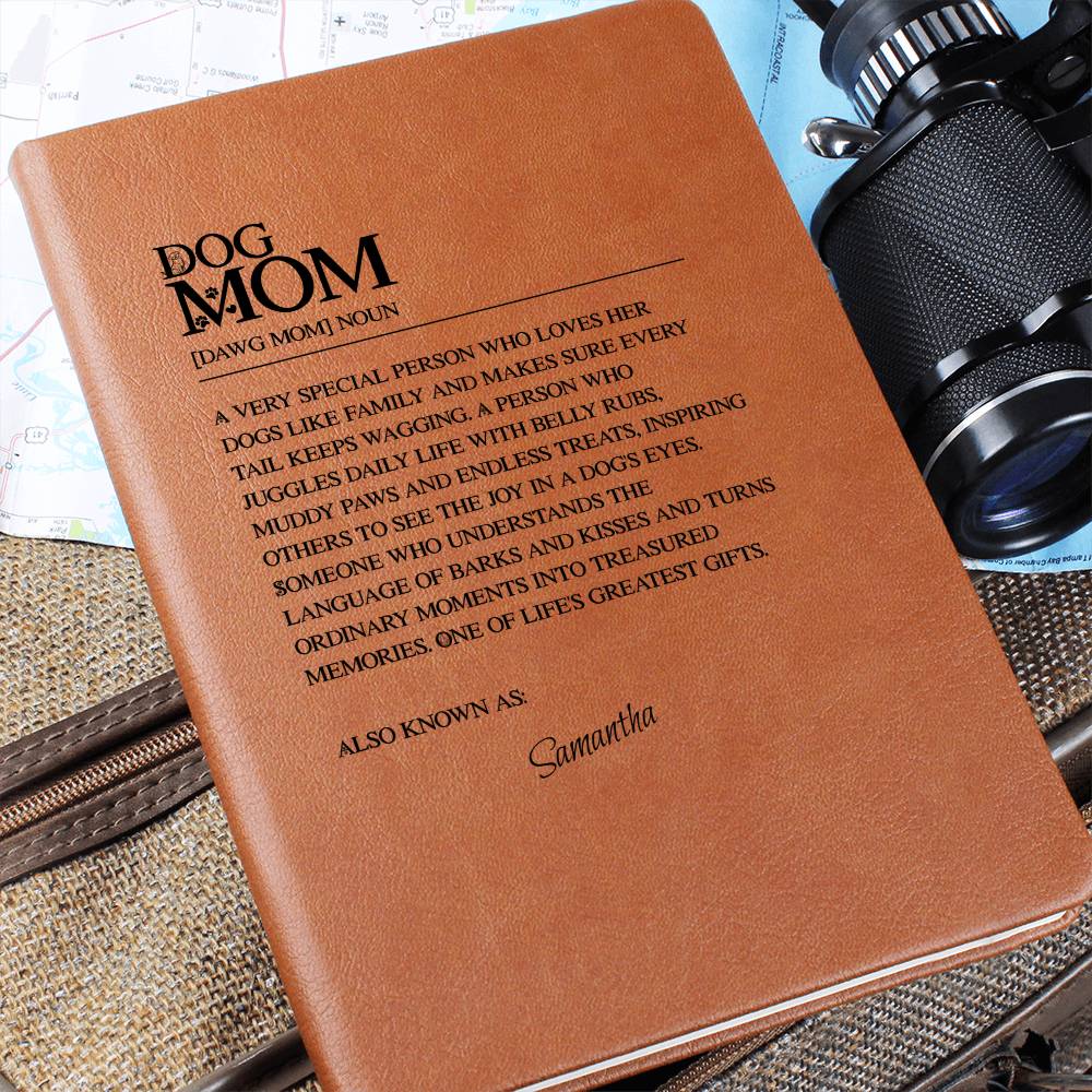 Brown leather notebook with 'Dog Mom' definition and 'Samantha' on a textured surface with camera equipment.