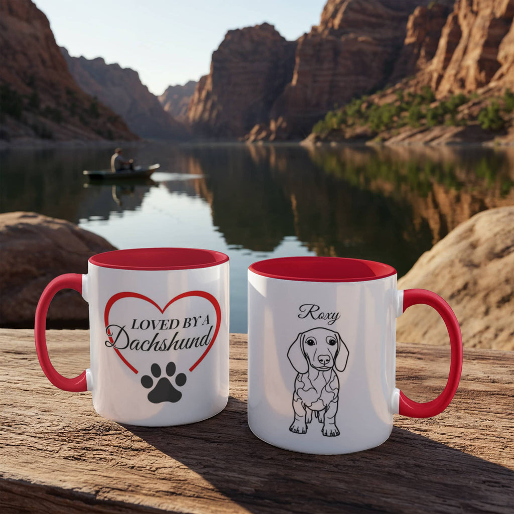 Two mugs with red interior and handles on a wooden surface with a scenic background of a lake and mountains.
