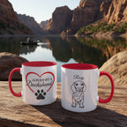 Two mugs with red interior and handles on a wooden surface with a scenic background of a lake and mountains.
