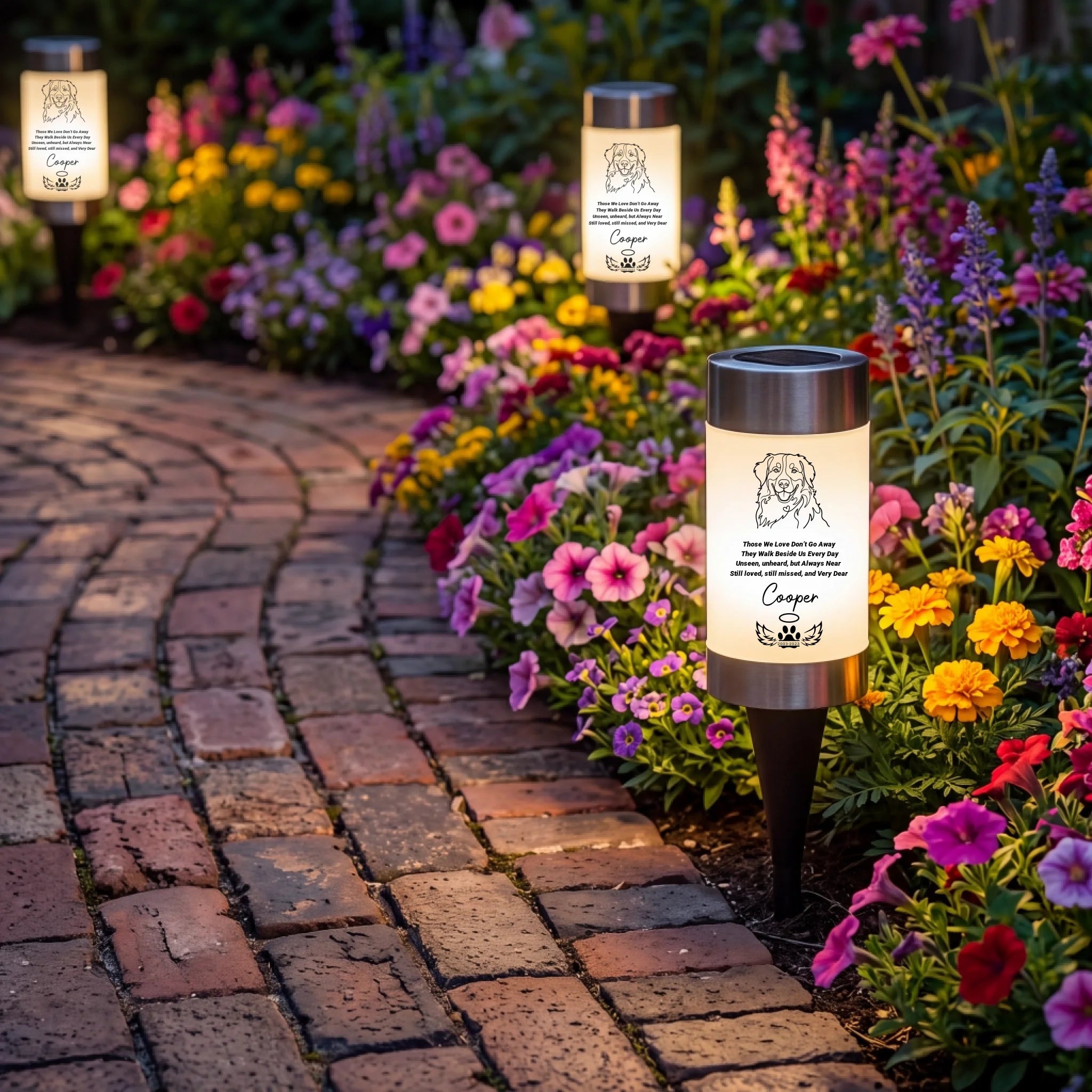 Three custom solar pathway lights. The lights feature a glowing warm-white cylindrical body with a black top cap and stake, and a printed custom memorial design featuring a dog portrait and their name