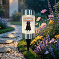 A cylindrical solar garden light with a black dog and 'Happy Halloween' graphic, set in a garden pathway during a rainy evening.