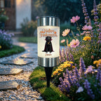 A cylindrical solar garden light with a black dog and 'Happy Halloween' graphic, set in a garden pathway during a rainy evening.