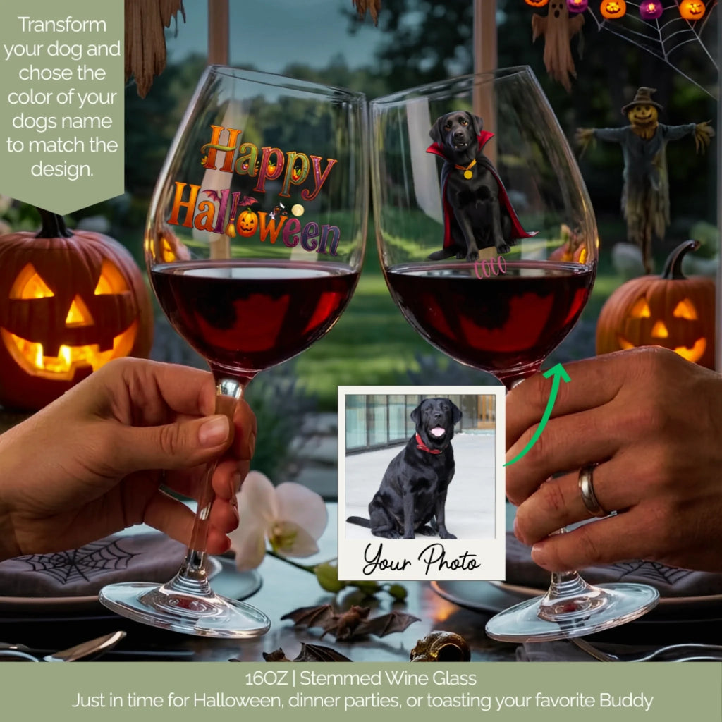 Two hands hold decorated 16oz stemmed wine glasses filled with red wine at a Halloween-themed table. One glass has a colorful 'Happy Halloween' design, and the other features a photo of a black dog with a vampire cape.