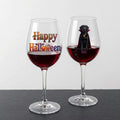 Two clear wine glasses filled with red wine, displayed on a dark surface against a light gray background. The left glass has 'Happy Halloween' printed on it, and the right glass features a black dog wearing a vampire costume with the word 'coco' below.