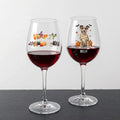 Two clear wine glasses filled with red wine, displayed on a dark slate surface against a light gray background. The left glass has a colorful 'Happy Halloween' design, and the right glass is personalized with the name 'MOLLY' above a cartoon dog dressed as a mummy with pumpkins and bats.