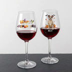 Two clear wine glasses filled with red wine, displayed on a dark slate surface against a light gray background. The left glass has a colorful 'Happy Halloween' design, and the right glass is personalized with the name 'MOLLY' above a cartoon dog dressed as a mummy with pumpkins and bats.