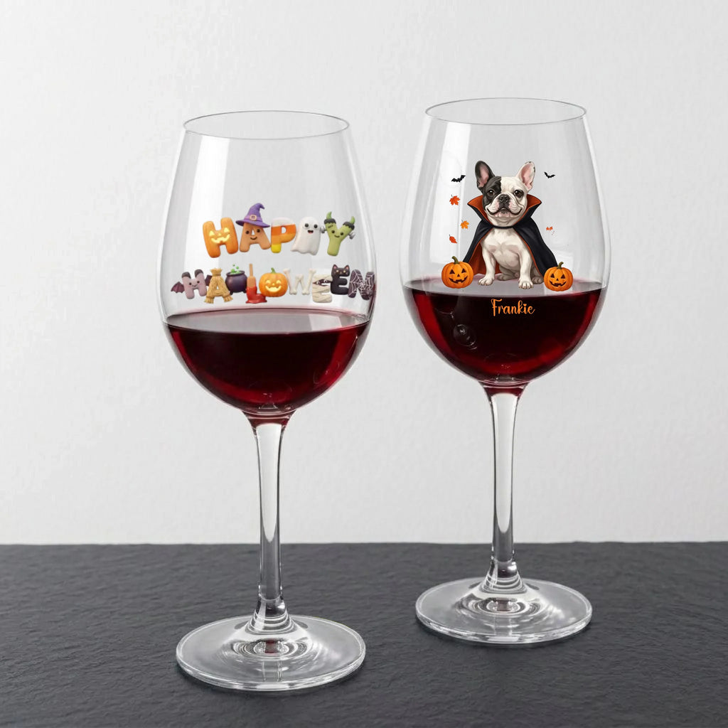 Two clear wine glasses filled with red wine, displayed on a dark surface against a light gray background. The left glass has a colorful 'Happy Halloween' decoration, and the right glass is personalized with a cartoon French Bulldog and the name 'Frankie' in gold script.