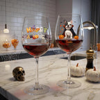 Two clear wine glasses filled with red wine sit on a marble kitchen counter. The left glass has a colorful 'Happy Halloween' decoration, and the right glass features a cartoon French bulldog wearing a vampire cape with the name 'Frankie' printed below.