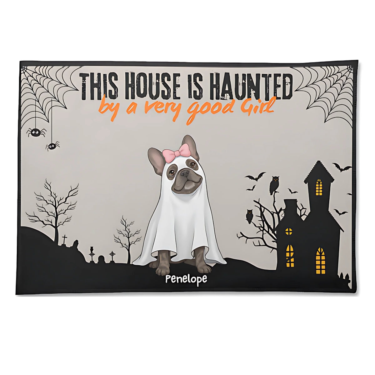 A rectangular Halloween-themed mat or rug with a printed design featuring a French bulldog dressed as a ghost, the text 'THIS HOUSE IS HAUNTED by a very good Girl', a haunted house, spiderwebs, bats, and the name 'Penelope' at the bottom. The mat is shown against a plain white background.