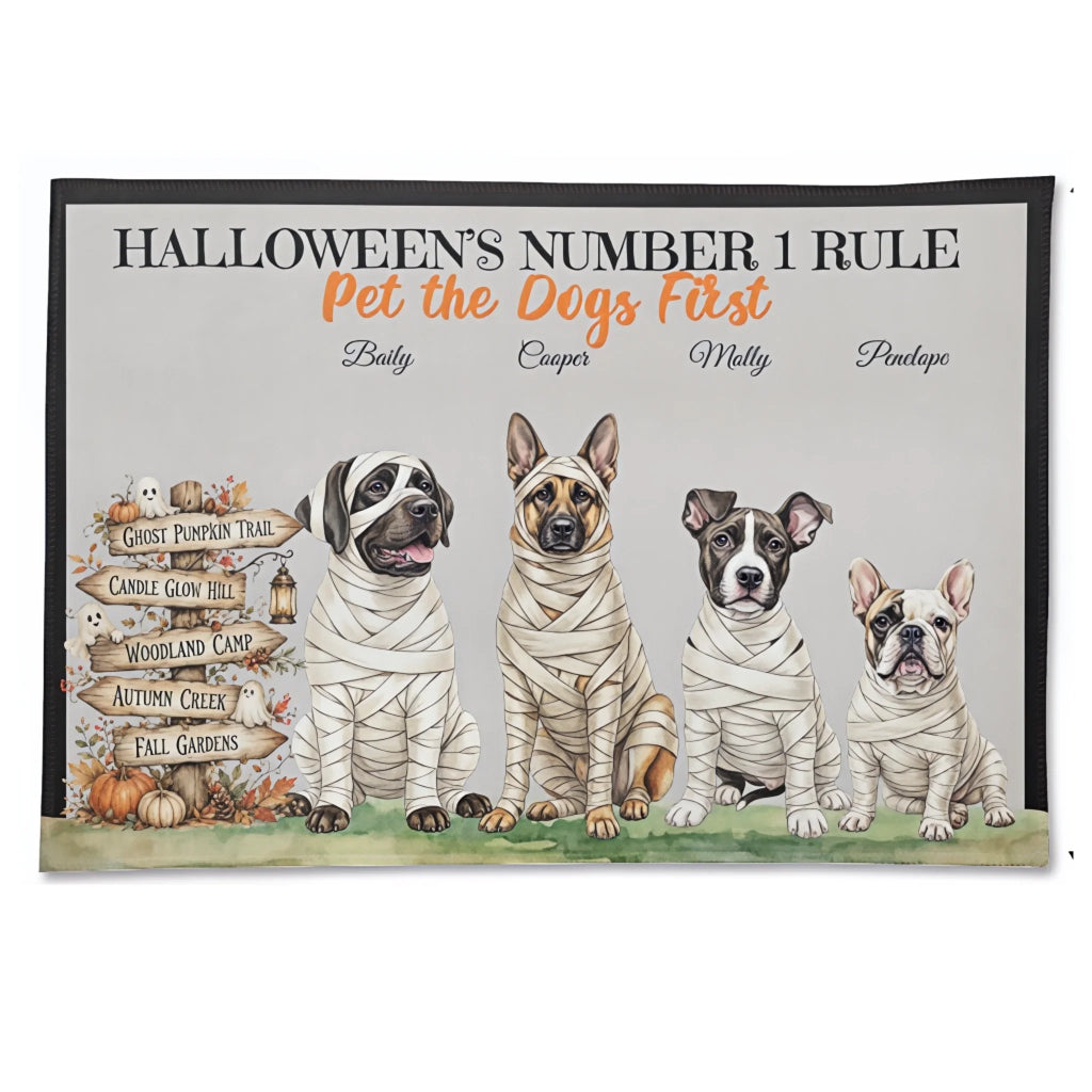 A rectangular decorative print or poster with a black border and the text 'HALLOWEEN'S NUMBER 1 RULE Pet the Dogs First' above four illustrated dogs dressed as mummies, plus a wooden sign listing Halloween trails. This is not a real environment photo; it is a clean product-style presentation of wall art, so subject_type is Product/Packaging rather than Lifestyle or Scenery.