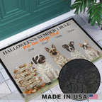 A rectangular doormat with a Halloween-themed design featuring four mummy dogs, the text 'HALLOWEEN'S NUMBER 1 RULE' and 'Pet the Dogs First', plus decorative fall signs and pumpkins. The mat is shown placed at a doorway on a tiled floor, with a black circular inset highlighting the printed pattern detail and a 'MADE IN USA' badge at the bottom.