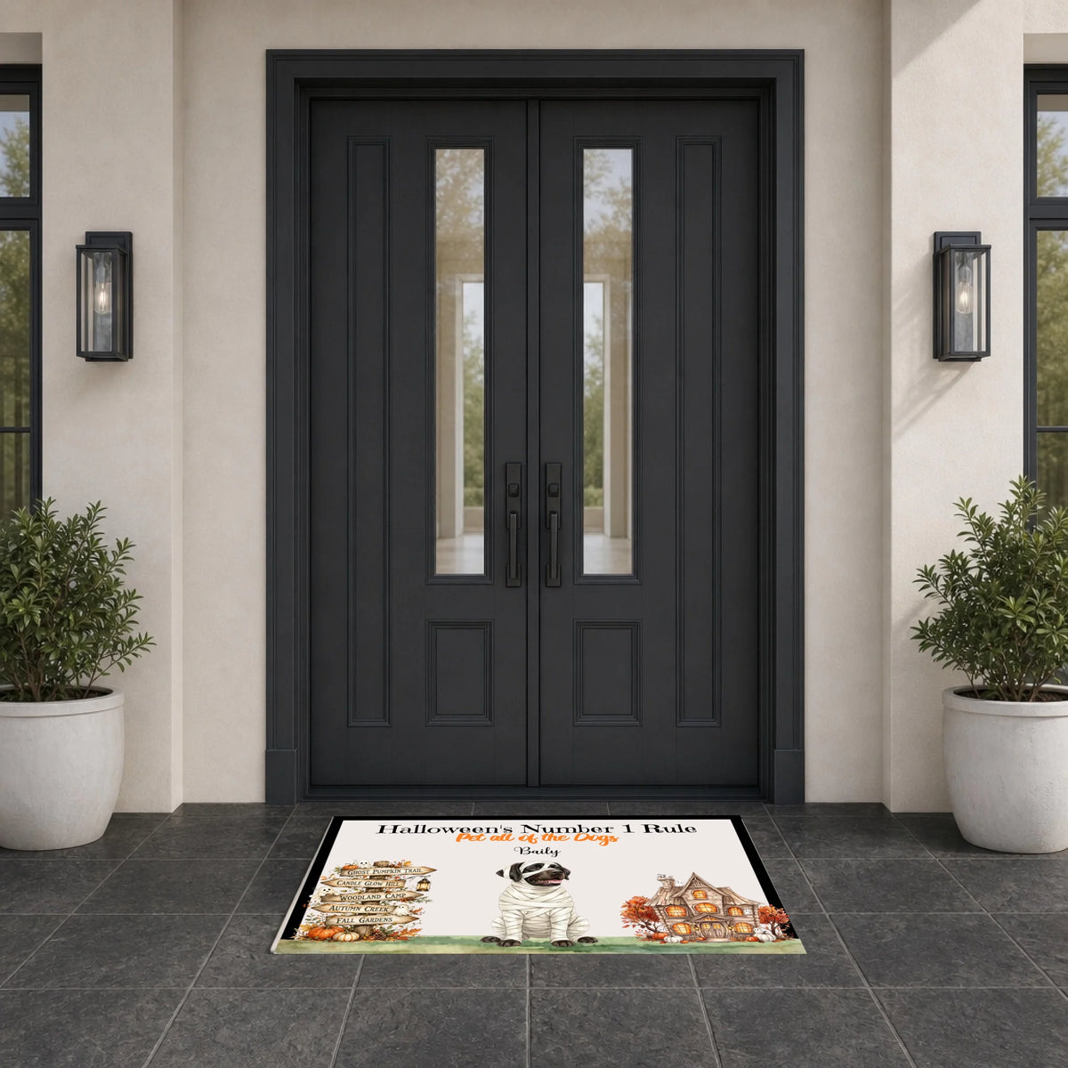 A rectangular front door doormat with a Halloween-themed illustration and the text 'Halloween Number 1 Bole' and 'Stay in the Fun' is placed in front of dark charcoal double front doors on a tiled entryway floor, flanked by potted plants and wall sconces.