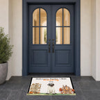 A rectangular Halloween-themed doormat with a cartoon mummy dog and autumn illustrations, placed in front of dark blue double doors on a tiled entryway floor.