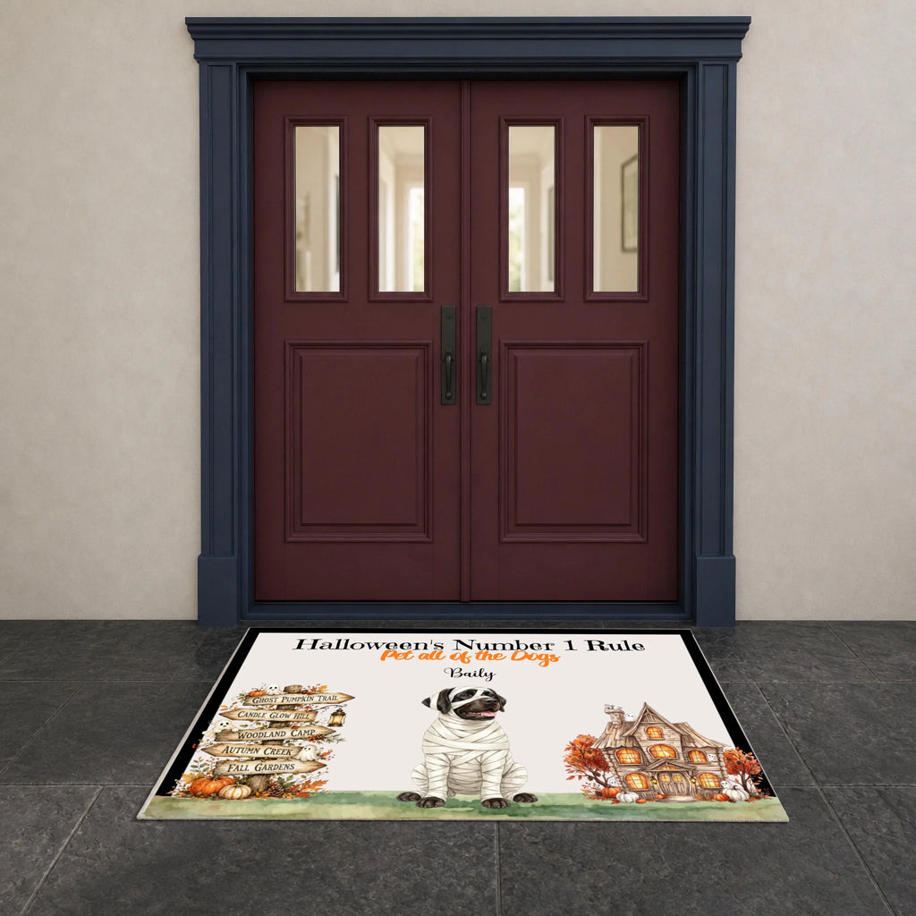 A personalized Halloween doormat featuring a mummled pug, a haunted house, pumpkins, and the text 'Halloween's Number 1 Rule. Get all the treats.