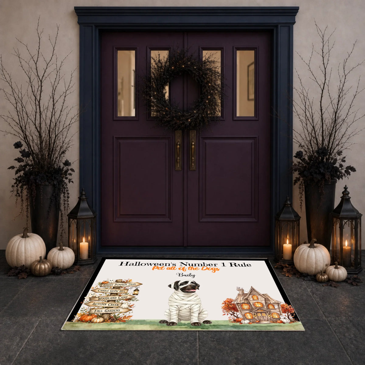 A rectangular Halloween-themed doormat displayed in front of a dark purple double door. The mat features a mummy dog, a haunted house, pumpkins, and the text 'Halloween's Number 1 Bule' and 'Pet of the Day' with the name 'Bule' printed on it.