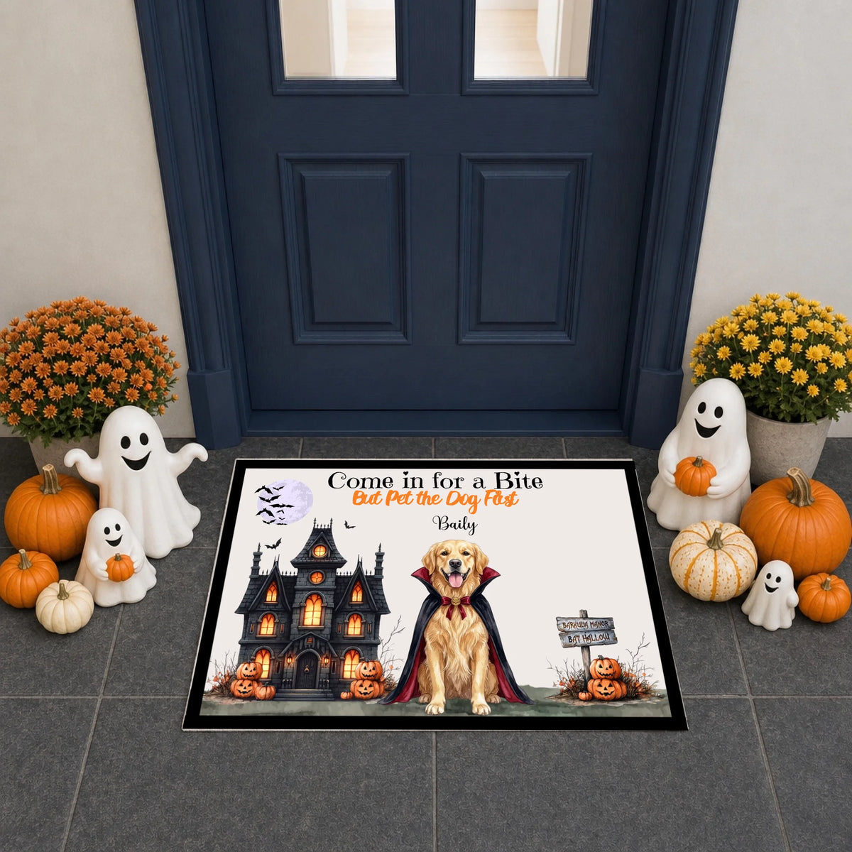 A Halloween-themed rectangular doormat displayed on a gray tiled porch in front of a dark blue door. The mat features a golden retriever dressed as a vampire in front of a haunted house, with pumpkins, ghosts, and the text 'Come in for a Bite But Put the Dog First' by 'Dusty'.