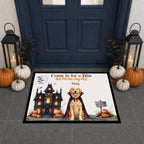 A rectangular Halloween-themed doormat displayed in front of a dark blue front door. The mat features a golden retriever dressed as a vampire in front of a haunted house, with pumpkins, bats, and the text 'Come in for a Bite Eat Pet the Dog First: Baby'.