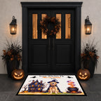 A Halloween-themed doormat displayed in front of a black double door. The mat features a cartoon dog in a witch hat, a haunted house, a cauldron, and the text 'Some Witches I Know'.