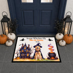 A rectangular Halloween-themed doormat displayed in front of a dark blue front door. The mat features a golden retriever dog in a witch hat and cape next to a haunted house and a cauldron, with the text 'Some Witches Fly Mine Or Yours Daily' and the name 'Emily' printed on it.