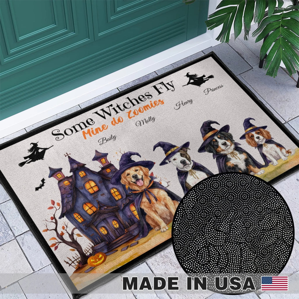 A Halloween-themed doormat with illustrated dogs in witch hats, a haunted house, bats, and the text 'Some Witches Fly Mine do Enemies' displayed on a tiled entryway floor in front of a teal door. A circular inset shows a close-up of the black dotted pattern, and a 'MADE IN USA' badge appears at the bottom.