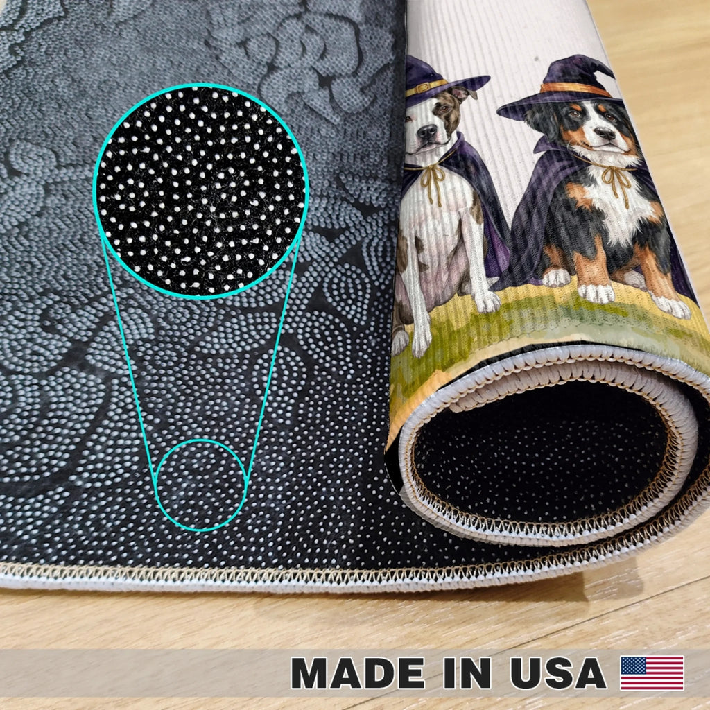 A rolled-up black yoga mat with a white dotted pattern and a printed illustration of two dogs dressed as witches, shown on a light wood floor. A circular zoom-in highlights the detailed dot pattern.