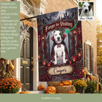 A Halloween-themed custom dog flag displayed on a front porch. The flag features a photo of a white and black dog dressed as a vampire with the text 'Fangs for Visiting' and a customizable name 'Cooper'.