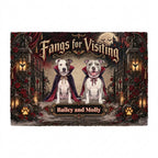 A rectangular decorative mat or plaque featuring two pitbull-type dogs in vampire capes seated in front of a gothic gate, with the text 'Fangs for Visiting' and 'Bailey and Molly.' The design includes red roses, lanterns, bats, and a full moon on a dark background.