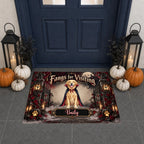 A Halloween-themed doormat featuring a golden retriever dressed as a vampire, surrounded by gothic lanterns, roses, and the text 'Fangs for Visiting' and 'Bailey'. The mat is displayed on a gray tiled floor in front of a dark blue front door, flanked by decorative pumpkins and lanterns.