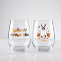 Two personalized Halloween stemless wine glasses on marble, one with 'Happy Halloween' lettering, one with a ghost-costume dog with pumpkins and pet name