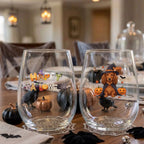Pair of personalized Halloween stemless wine glasses with a witch-costume dog with pumpkins on a dining table set for a Halloween party