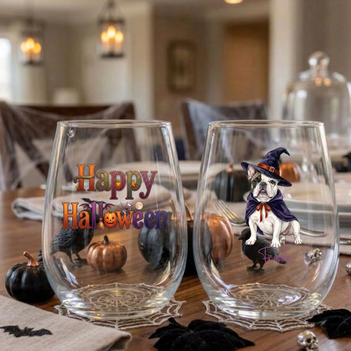 Pair of personalized Halloween stemless wine glasses with a watercolor witch-costume dog on a dining table set for a Halloween party