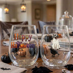 Pair of personalized Halloween stemless wine glasses with a watercolor mummy-costume dog on a dining table set for a Halloween party