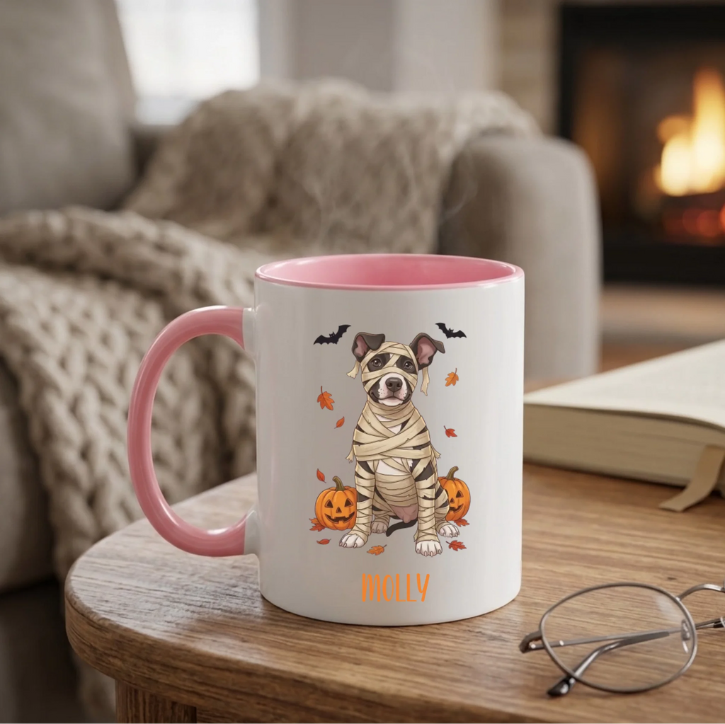 Personalized mummy dog Halloween coffee mug with pink handle on a side table by a cozy fireplace