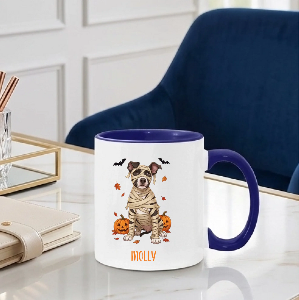 Personalized mummy dog Halloween coffee mug with midnight blue handle on a desk beside a blue chair