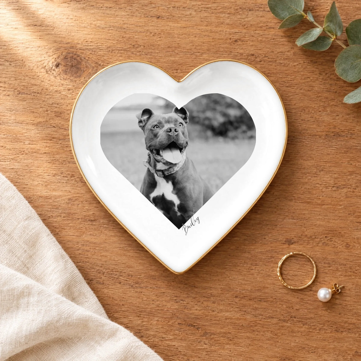 Black and white pet photo heart ring dish on a wooden table with linen and eucalyptus
