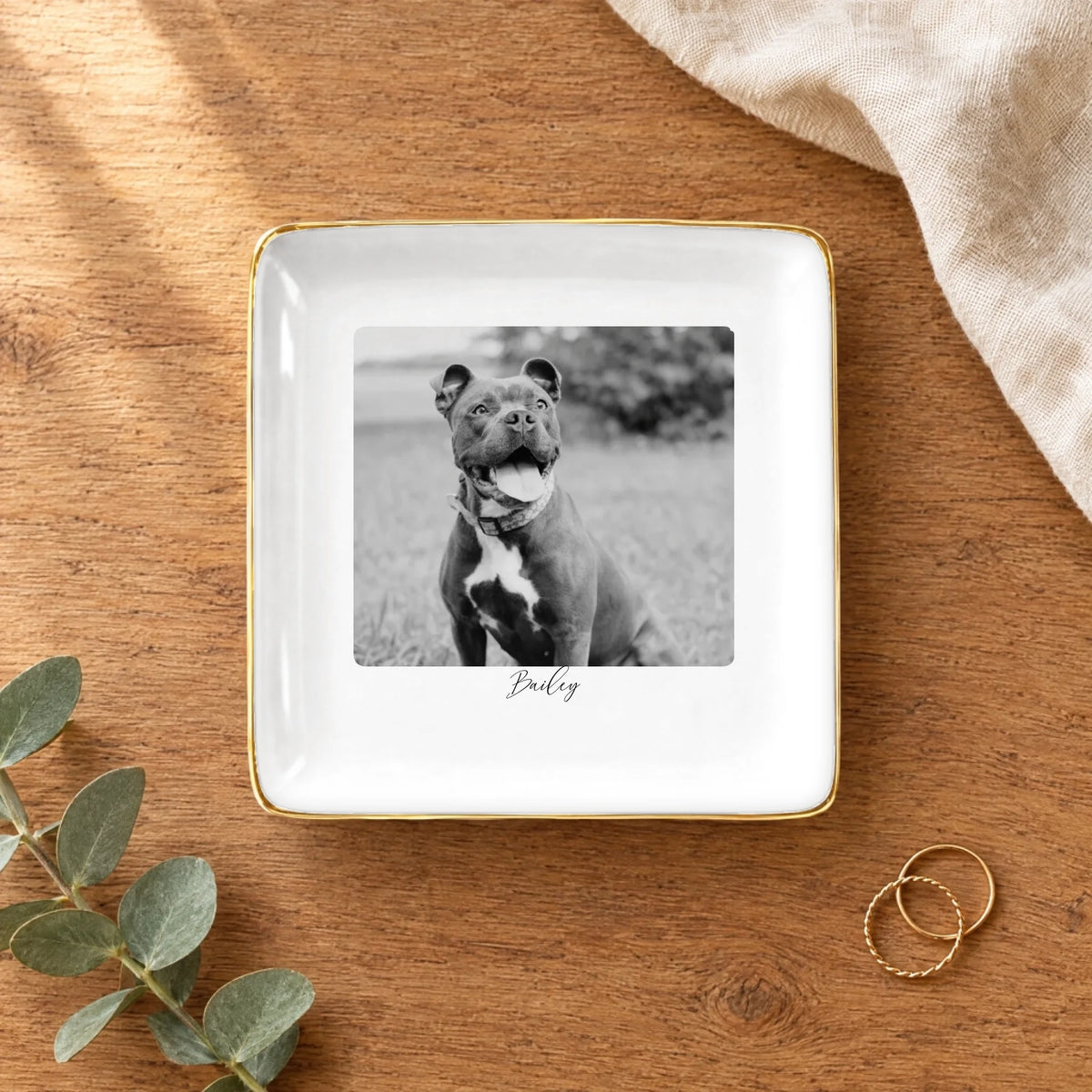 Black and white pet photo square ring dish on a wooden table with linen and eucalyptus