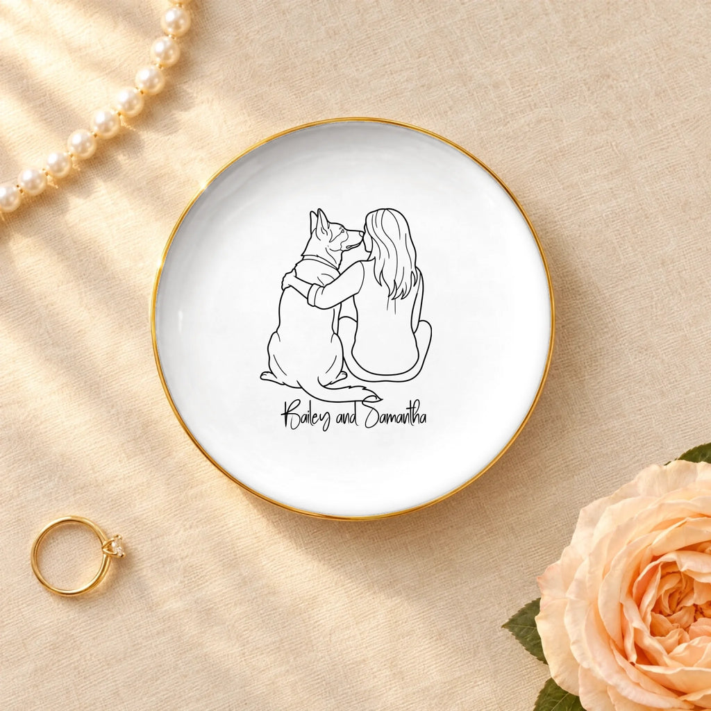 Personalized line drawing of a woman and her dog on a round ceramic ring dish with gold rim