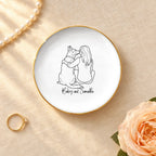 Personalized line drawing of a woman and her dog on a round ceramic ring dish with gold rim