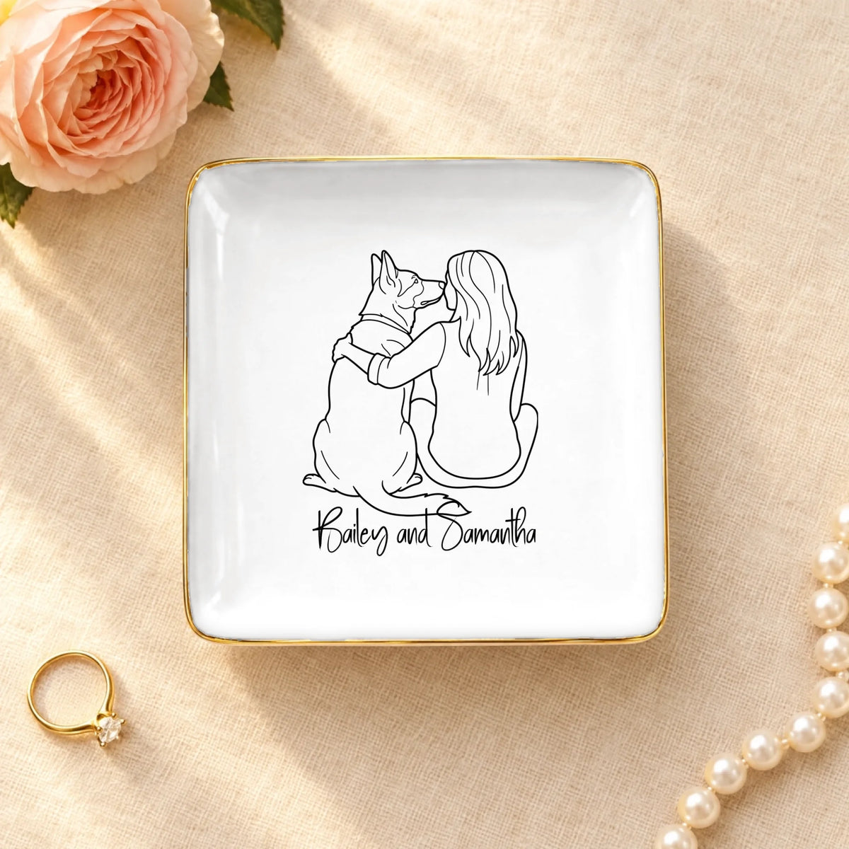 Personalized line drawing of a woman and her dog on a square ceramic ring dish with gold rim