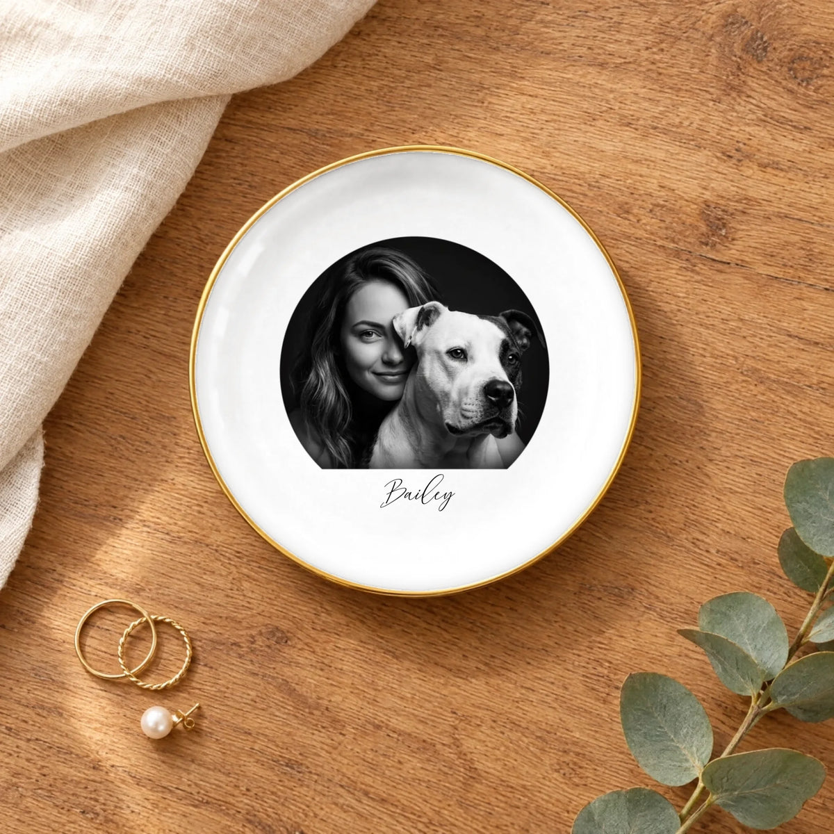 Black and white studio portrait round ring dish on a wooden table with linen and eucalyptus
